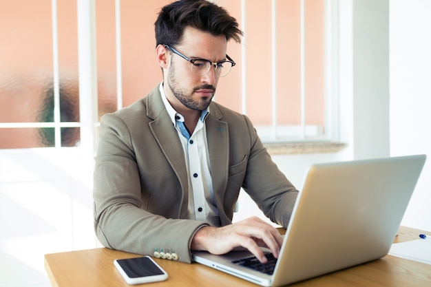 Foto de hombre de negocios joven y guapo que trabaja con el portátil en la oficina.