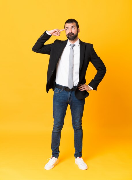 Foto de hombre de negocios sobre amarillo aislado haciendo el gesto de locura poniendo el dedo en la cabeza