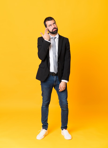 Foto de hombre de negocios sobre amarillo aislado con problemas para hacer el gesto de suicidio