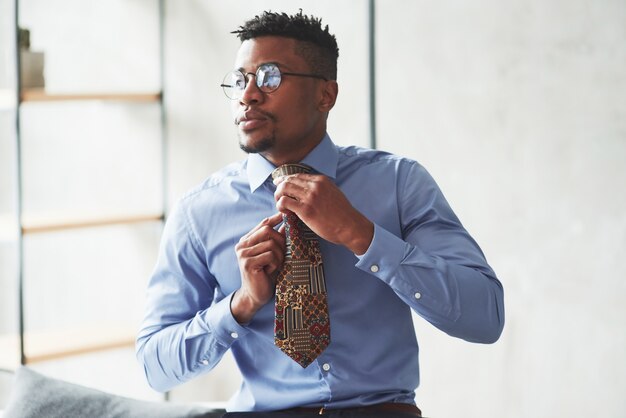 Foto de hombre negro elegante vistiendo ropa y preparándose para el trabajo