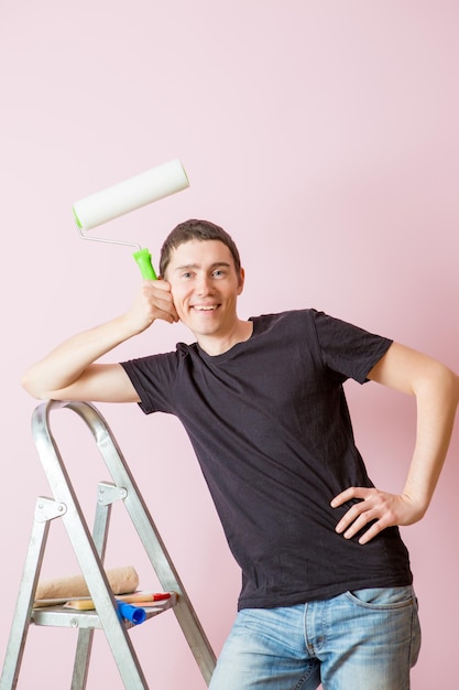 Foto de hombre con rodillo de pintura al lado de la escalera