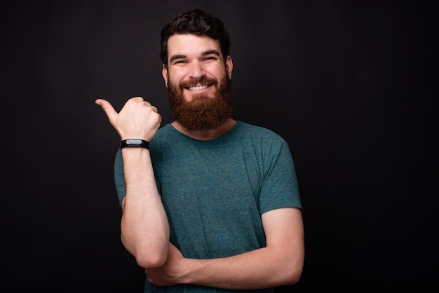 Foto de hombre sonriente con barba apuntando lejos en copyspace