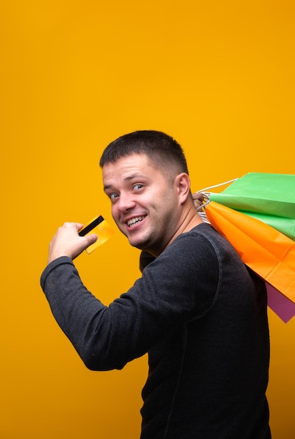 Foto de hombre con tarjeta bancaria y bolsas de compras multicolores