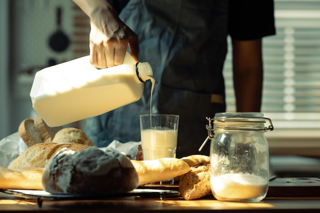 Una foto de un hombre vertiendo leche en un vaso preparando un desayuno saludable en la cocina