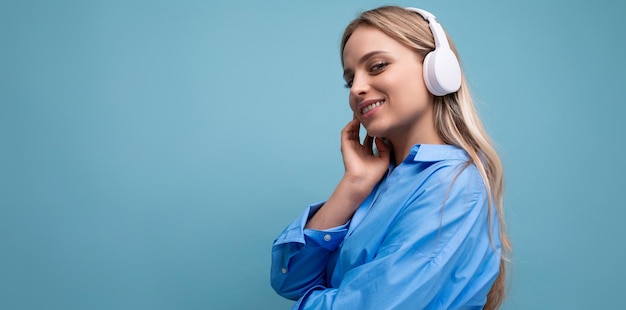 Foto horizontal de una chica atractiva con grandes auriculares inalámbricos escuchando música con placer