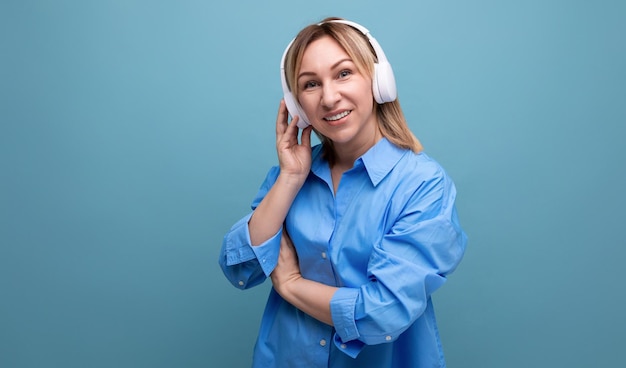 Foto horizontal de uma jovem adorável em uma camisa casual ouvindo um podcast em grande branco