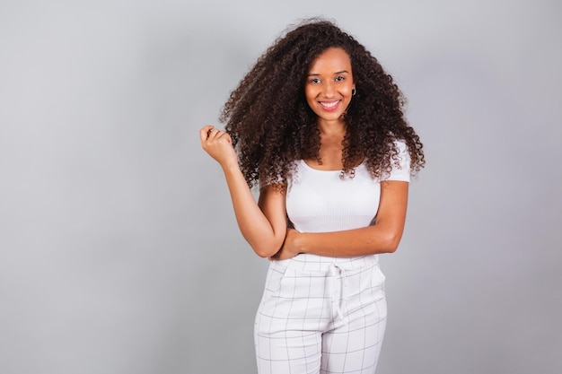 Foto horizontal hermosa mujer brasileña negra vestida con ropa casual blanca sonriendo