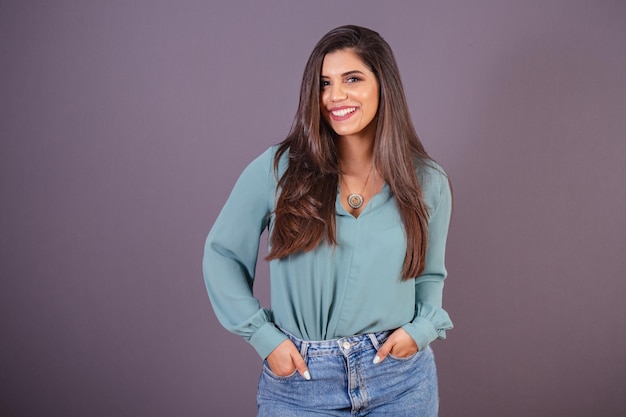 Foto horizontal Hermosa mujer brasileña con ropa casual Jeans y camisa verde manos en el bolsillo sonriendo