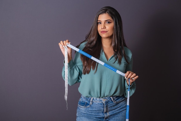 Foto horizontal Hermosa mujer brasileña con ropa casual Jeans y camisa verde nutricionista sosteniendo cinta métrica