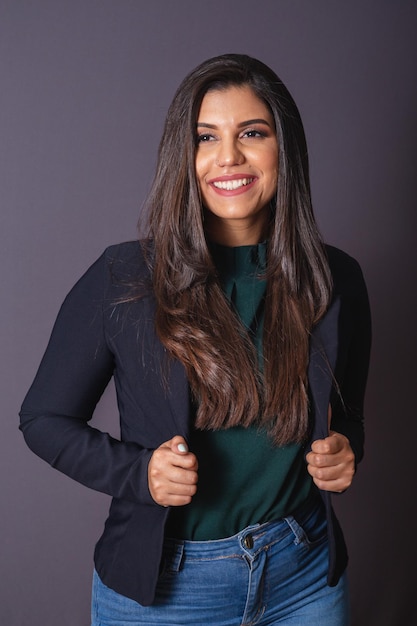 Foto horizontal Hermosa mujer brasileña en ropa casual negro blazer jeans manos en la cintura