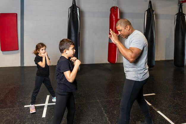 Foto horizontal de niños de primaria con su maestro en una escuela de boxeo calentándose Concepto deportivo