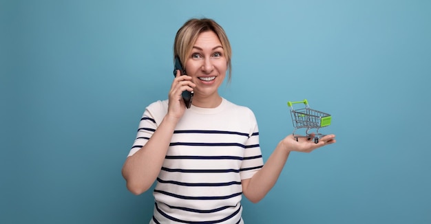 Foto horizontal para banner de uma compradora atraente falando no telefone segurando o carrinho de compras