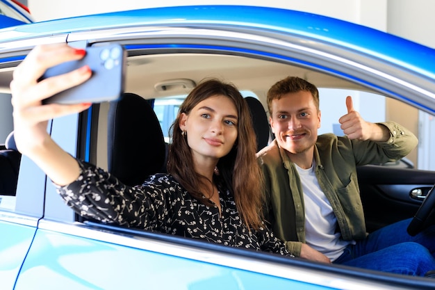 Foto in einem neuen Auto Ein junges Paar macht ein Selfie Kauf eines neuen Luxusautos bei einem Händler