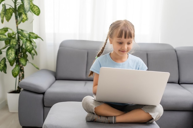 Foto in voller Größe des erstaunten Kindes sitzt mit gefalteten, gekreuzten Beinen am Arbeitscomputer und erhält eine Benachrichtigung über soziale Medien.