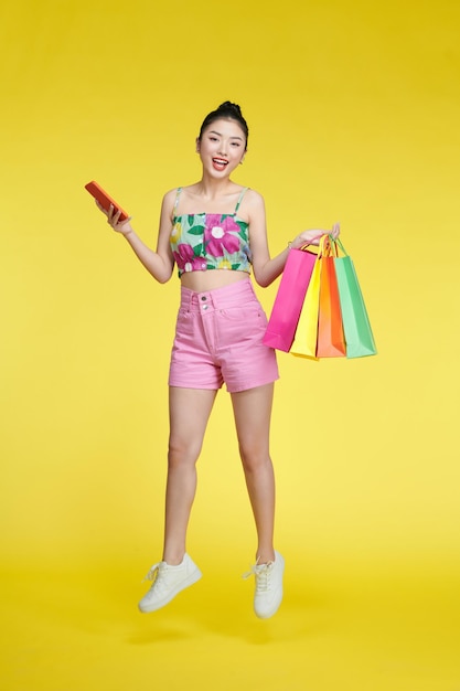 Foto in voller Länge der hübschen positiven Dame, die Speicher-Mall-Pakete verwendet, verwenden Telefon