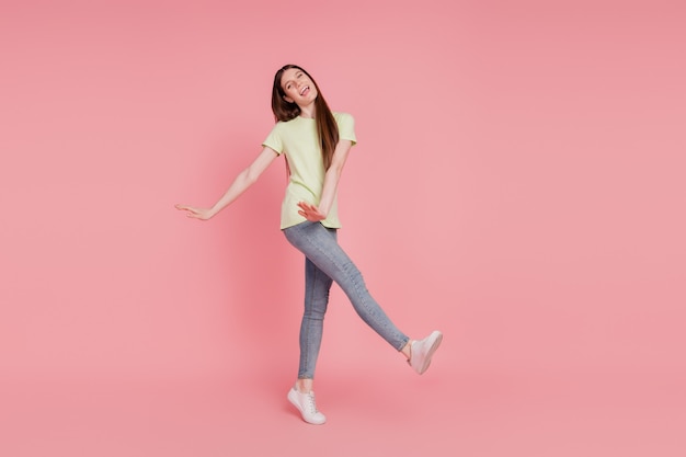 Foto in voller Länge der jungen fröhlichen Frau glückliches positives Lächeln haben Spaß verspielt isoliert über rosafarbenem Hintergrund