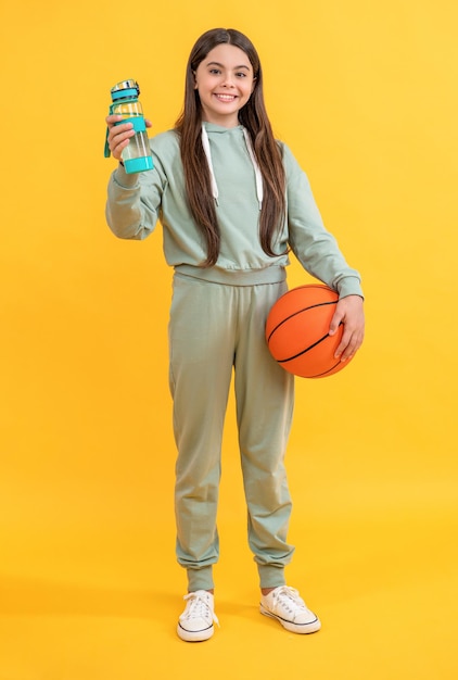 Foto in voller Länge des jugendlich Basketballmädchens mit Wasserflasche jugendlich Basketballmädchen lokalisiert auf Gelb