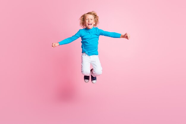 Foto in voller Länge von kleinen Kindern mit offenem Mund tragen blaue Rollkragenhosen Turnschuhe isoliert pastellrosa Farbhintergrund