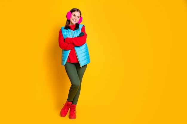 Foto in voller Länge von positiven, fröhlichen Mädchen, die Hände überqueren, grüne Handschuhe sehen Exemplar aus