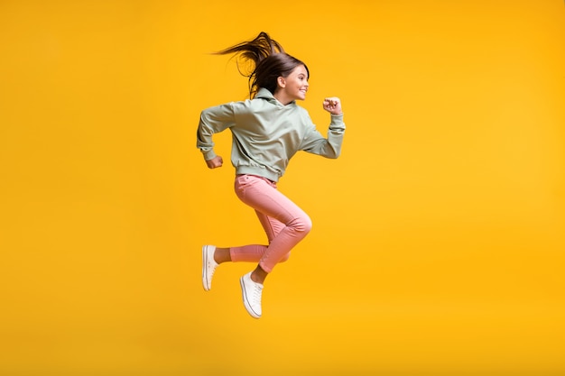 Foto in voller Länge von Schulleuten in der Luft, die mit der Faust springen, die auf gelbem Hintergrund isoliert ist