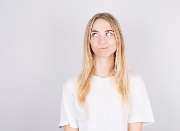 Foto de increíble chica rubia mirando hacia el espacio vacío pensando profundamente en gris