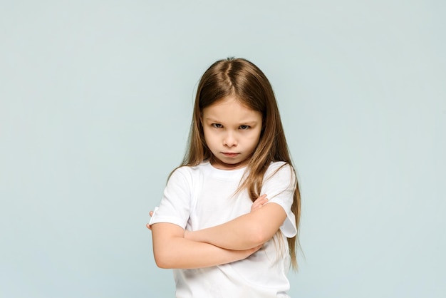 Foto de una infeliz y triste niña que se siente aburrida y ofendida aislada de fondo azul