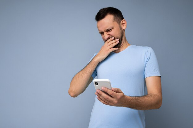 Foto de insatisfecho sorprendido joven guapo con barba vistiendo camiseta azul todos los días