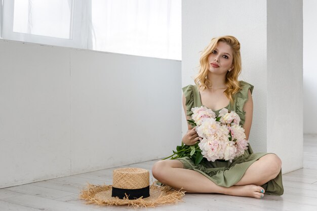 Foto interna de uma linda garota segurando peônias brancas e rosas, uma mulher atraente com um grande buquê