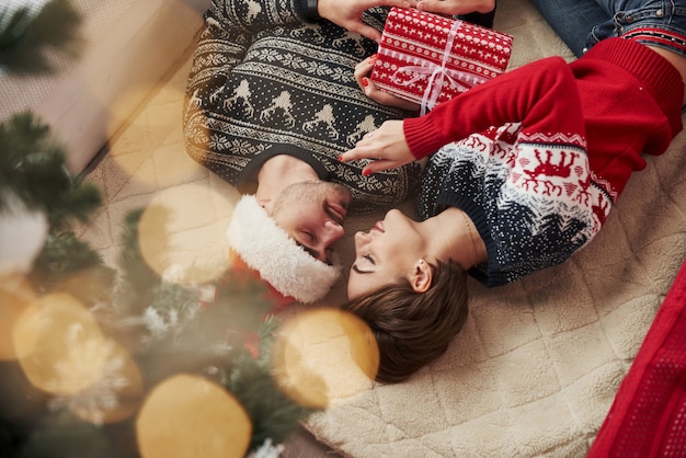 Foto invertida de una joven pareja que celebra el año nuevo y tiene una caja de regalo en las manos