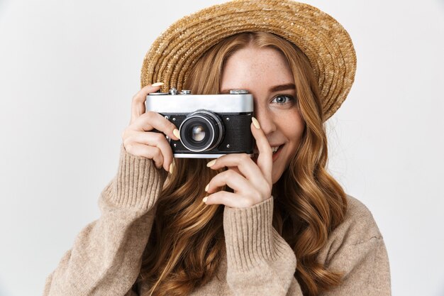 Foto de una joven adolescente linda feliz contenta posando aislada sobre la pared de la pared blanca sosteniendo la cámara fotografiando.