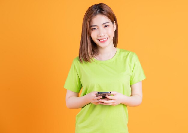 Foto de una joven asiática usando un teléfono inteligente en el fondo