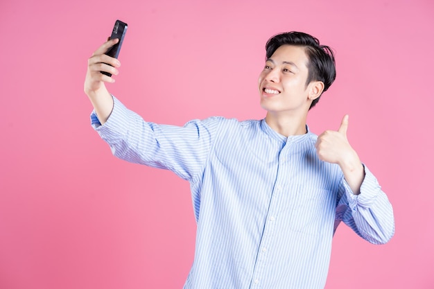 Foto de un joven asiático usando un teléfono inteligente en el fondo