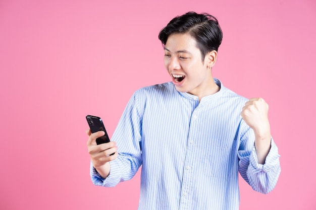 Foto de un joven asiático usando un teléfono inteligente en el fondo