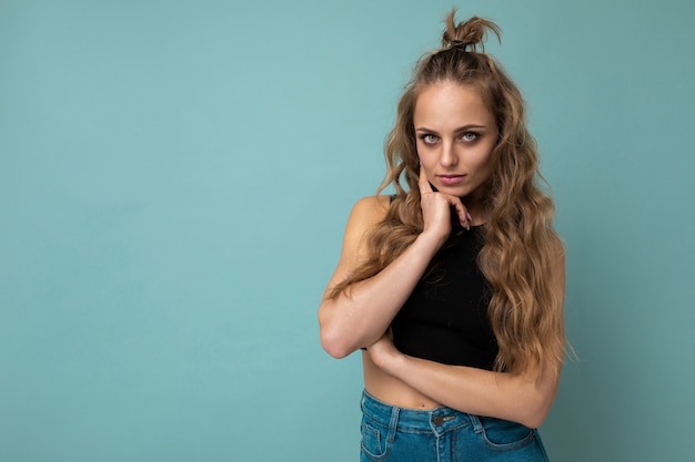 Foto de joven y atractiva mujer rubia de moda europea vistiendo camiseta negra superior aislado sobre azul