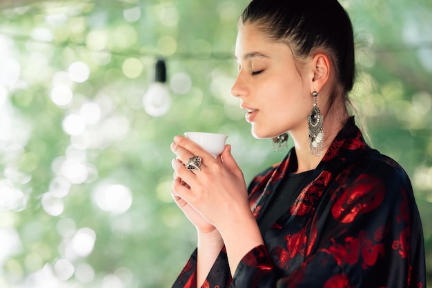 Una foto de una joven bebiendo de un tazón de té