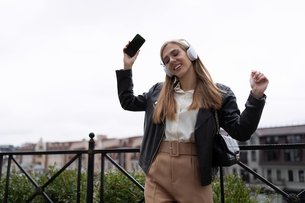 Foto de una joven bloguera escuchando un podcast con auriculares en la calle