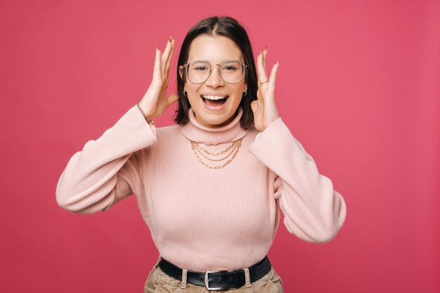 Foto de una joven conmocionada y asombrada sobre fondo rosa