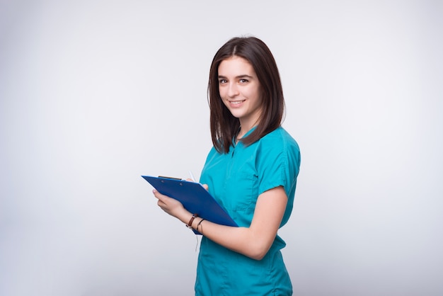 Foto foto de una joven doctora o dentista estudiante está escribiendo algo en un tablero de papel azul.