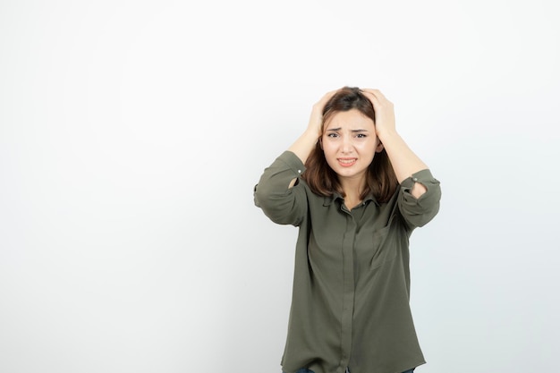 Foto de una joven con dolor de cabeza sobre una pared blanca. foto de alta calidad