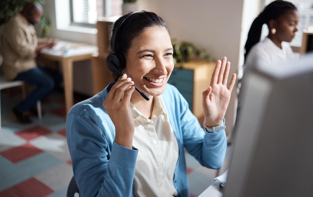 Una foto de una joven empresaria usando un auricular y una computadora y luciendo emocionada en una oficina moderna