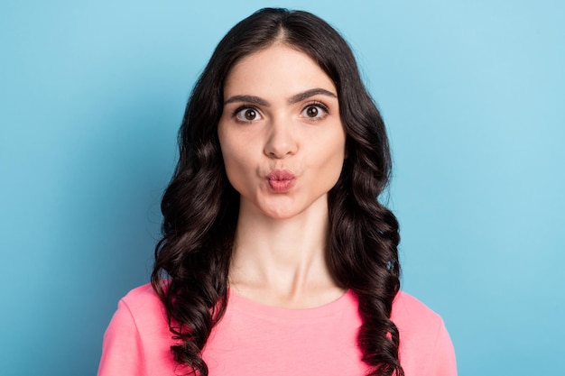 Foto de una joven encantadora con labios fruncidos que envían cosmetología de beso de aire aislada sobre fondo de color azul