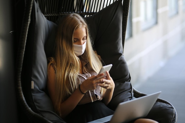 Foto de una joven enfocada usando un celular mientras está sentada en un café