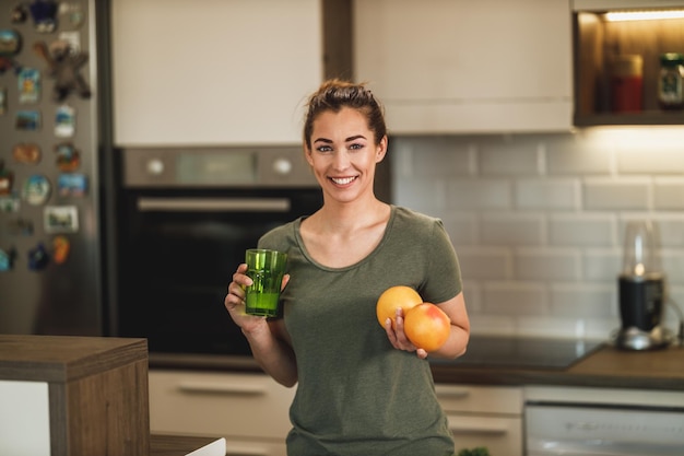 Una foto de una joven feliz preparando un desayuno de frutas en la cocina de su casa.