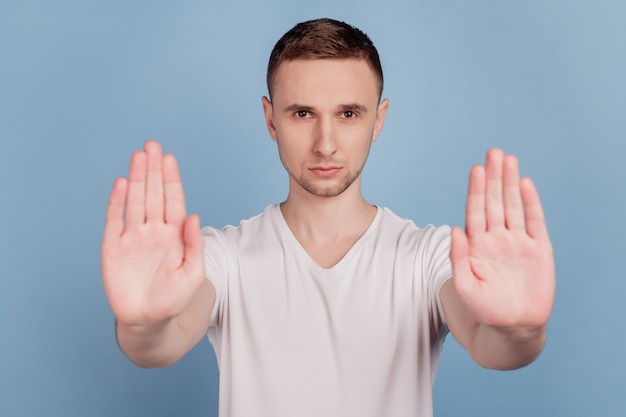 Foto de joven guapo infeliz triste mostrar ninguna señal de stop suficiente negar reglas aisladas sobre fondo de color azul