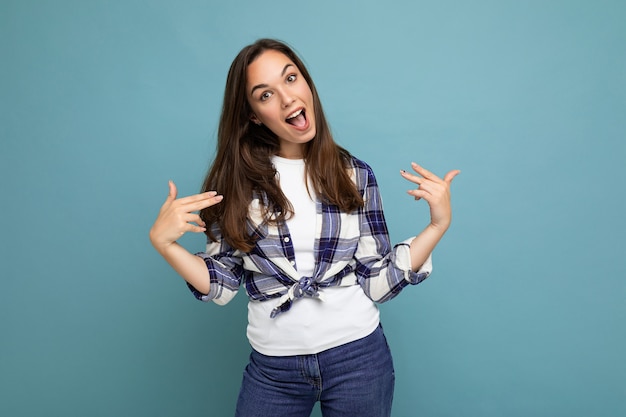 Foto de joven hermosa mujer morena sonriente encantadora positiva con emociones sinceras vistiendo camisa a cuadros de moda