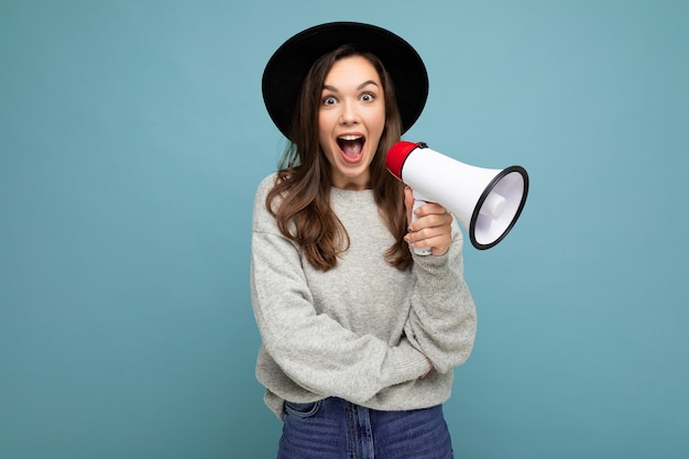 Foto de joven hermosa mujer morena sorprendida sorprendida positiva con sinceras emociones vistiendo