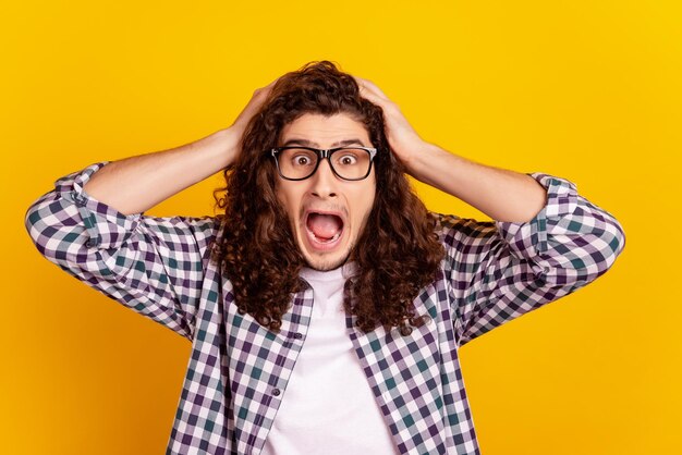 Foto de joven manos toque chead asombrado grito shoc miedo asustado aislado sobre fondo de color amarillo