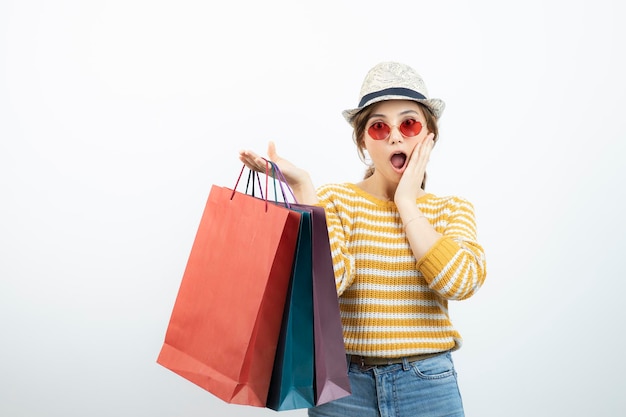 Foto de una joven morena con gafas de sol sosteniendo bolsas de compras. foto de alta calidad