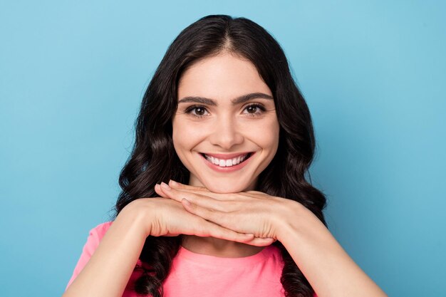 Foto foto de una joven mujer bonita con buen humor, los brazos tocan la barbilla, sueñan con la cara aislada sobre el fondo de color azul