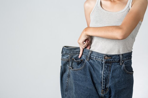 Foto de una joven mujer delgada en par de viejos jeans grandes